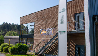 Außenansicht des Holz-Langen-Gebäudes mit moderner Holzfassade, großem Eingangsbereich und Freitreppe.