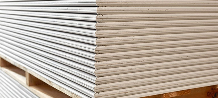 Gestapelte Gipsfaserplatten auf einer Holzpalette, bereit für den Einsatz im Trockenbau.