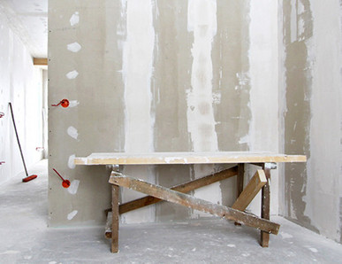 Rohbau mit verspachtelten Gipskartonwänden, Holzbock als Werkbank und sichtbaren Elektroinstallationen im Trockenbau.