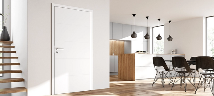 Helles, modernes Wohnambiente mit weißer Innentür, offener Küche und Essbereich mit schwarzen Stühlen.