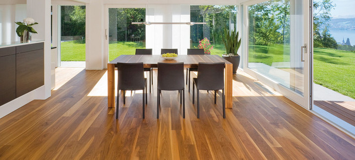 Die Küche ist mit massivem Boden ausgelegt. In der Mitte steht ein massiver Tisch mit Stühlen, und durch die Glasfenster sieht man den Ausgang zur Terrasse und zum Garten.